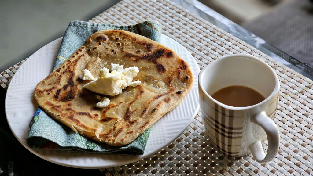 Appetizing flatbread with butter and tea served indoors as breakfast.